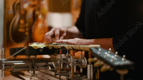 Guitar luthier hands polishing the frets on the fretboard  in a workshop