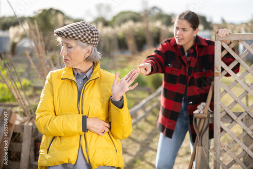 Photos Two upset young and old female neighbors disagree with each other while standing