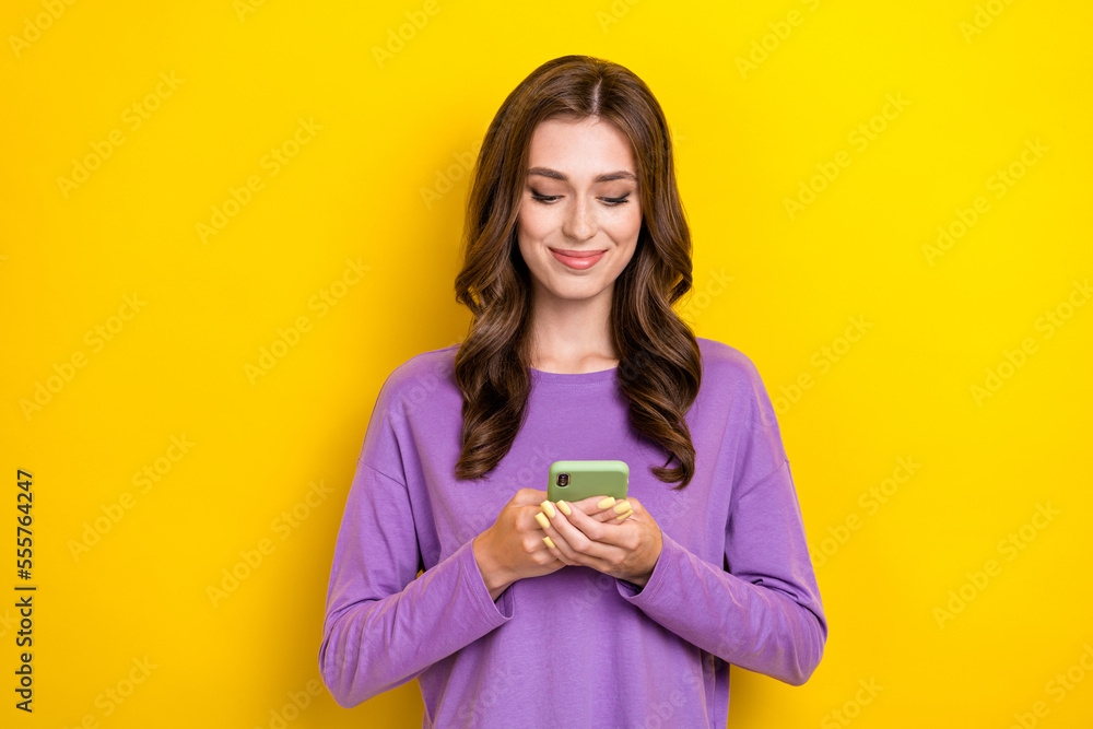 Photo of young satisfied user smartphone girl brown curly hair typing browsing more information about eshop isolated on yellow color background Photo of young satisfied user smartphone girl brown curly hair typing browsing more information about eshop isolated on yellow color background