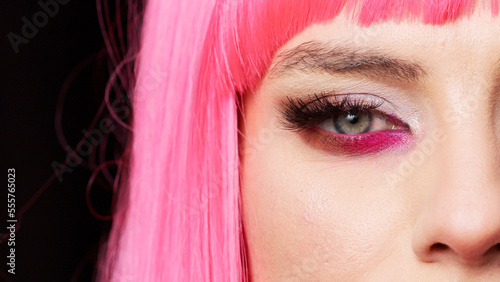 Macro shot of positive confident lady blinking on camera, having pretty eyes with colorful trendy makeup. Sensual attractive young model opening eyes and staring in studio. Extreme closeup.