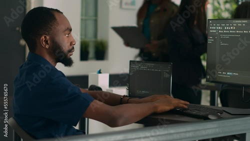 African american coder developing app interface with html code and script on terminal window, programming it language. System egineer using database information in development agency. photo