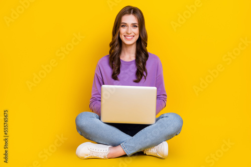 Full body portrait of cheerful nice lady sit floor use wireless netbook isolated on yellow color background © deagreez