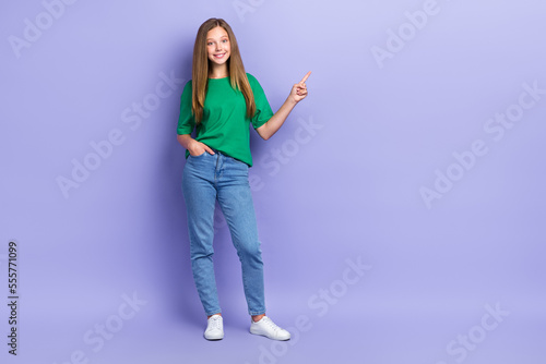 Full length photo of cheerful sweet small lady wear green t-shirt pointing finger empty space isolated violet color background
