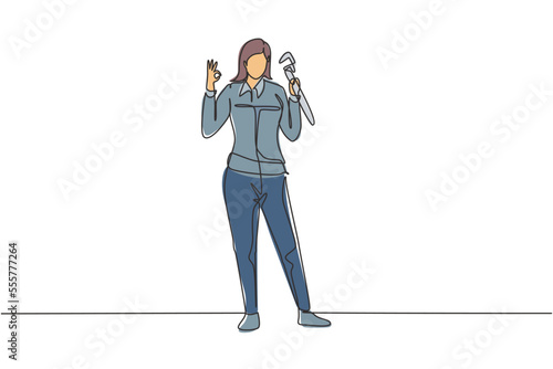Single continuous line drawing female plumber stands with gesture okay and holding carpentry tool fixing broken plumbing at home. Success business. One line draw graphic design vector illustration