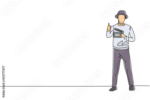 Single continuous line drawing film director stands with a thumbs-up gesture while holding the clapperboard to prepare the camera crew for shooting. One line draw graphic design vector illustration.