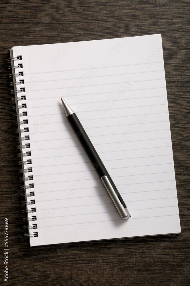 Close-up of blank notebook and writing pen on wooden background Close-up of blank notebook and writing pen on wooden background