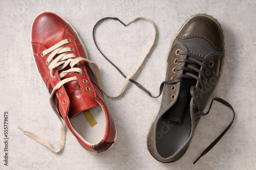 A man's shoe and a woman's shoe with laces tied together in a heart shape photo