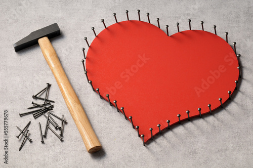 Nails outlinging large, wooden heart and hammer photo