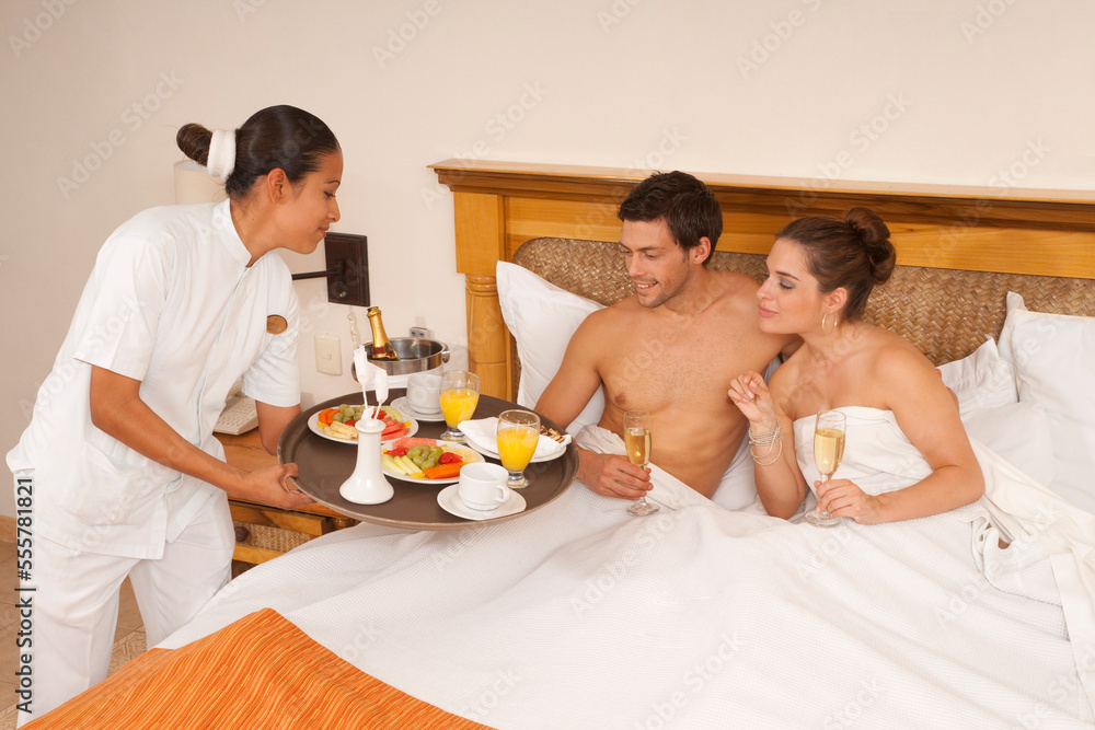 Couple being Served Breakfast in Bed in Hotel Couple being Served Breakfast in Bed in Hotel