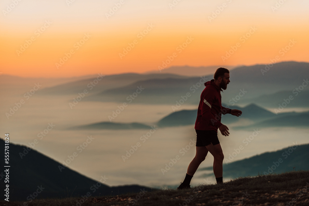 A man running on a mountain in the early morning as the sun rises