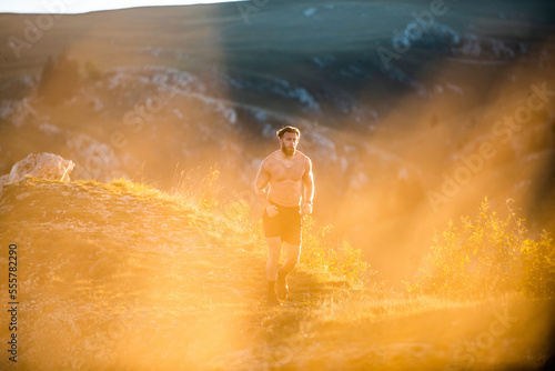 A man running on a mountain in the early morning as the sun rises