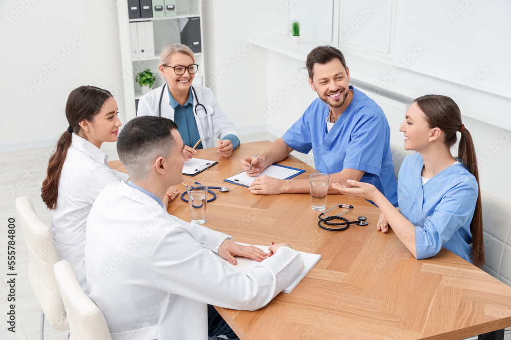 Obraz premium Medical conference. Team of doctors having discussion at wooden table in clinic