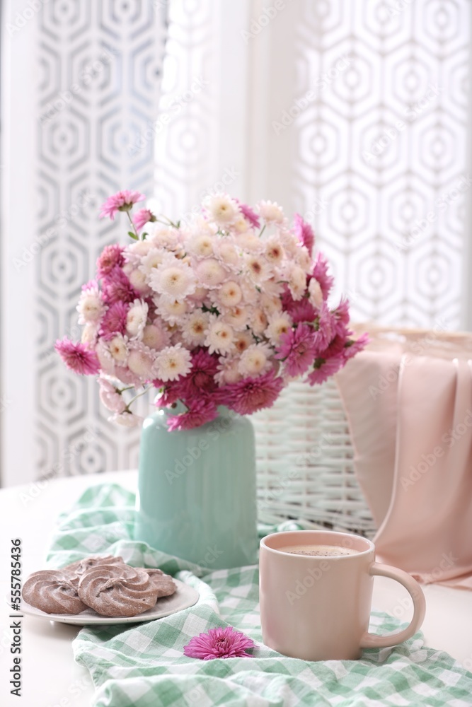 Cup of fresh coffee and beautiful bouquet on white table Cup of fresh coffee and beautiful bouquet on white table