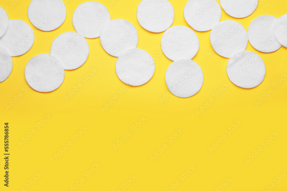 Soft clean cotton pads on yellow background, flat lay. Space for text