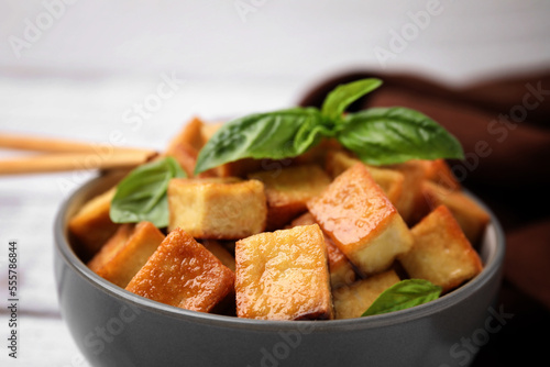 Bowl with delicious fried tofu and basil, closeup