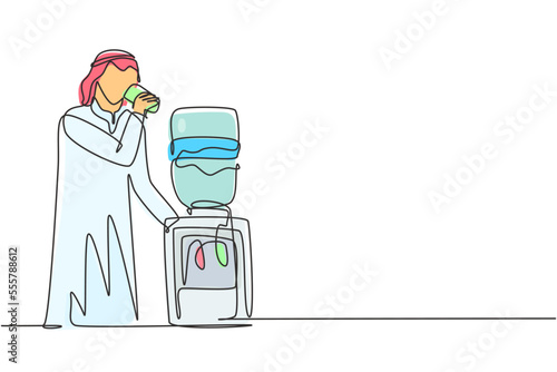 Single continuous line drawing young Arabian man drinking fresh water in glass while standing next to water dispenser filled with gallons of water. One line draw graphic design vector illustration
