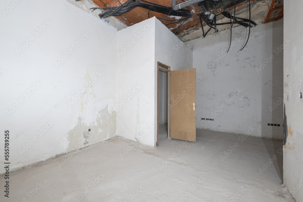 Rough premises with all exposed unfinished electrical piping and cement floors, brick pillars and half-plastered walls, outlet boxes on the walls and unpainted doors