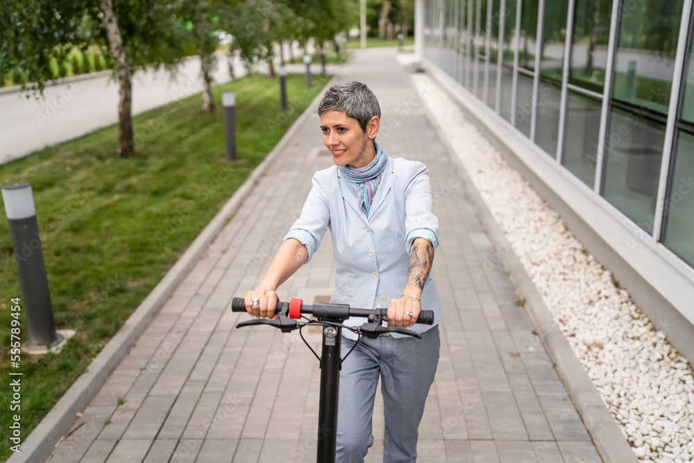 Obraz premium One woman mature senior adult female with eco electric kick scooter