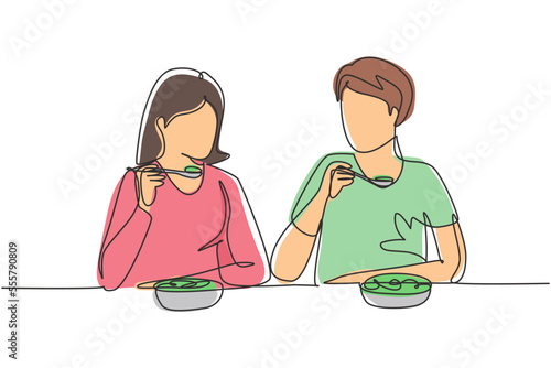 Single continuous line drawing young couple having salad meal around table. Happy male female sitting eating lunch together in restaurant. Dynamic one line draw graphic design vector illustration