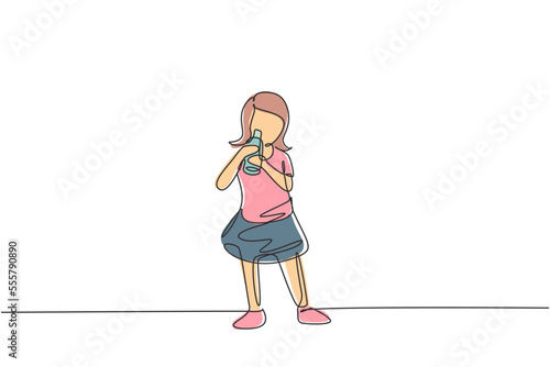 Continuous one line drawing girl standing while drinking milk in a bottle to fulfill her body's nutrition. Healthy lifestyles concept for kids. Single line draw design vector graphic illustration