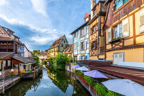 View of half timber homes and cafes from a boat on the Lauch canal in the historic medieval Petite Venice district of Colmar, France, in the Alsace region.