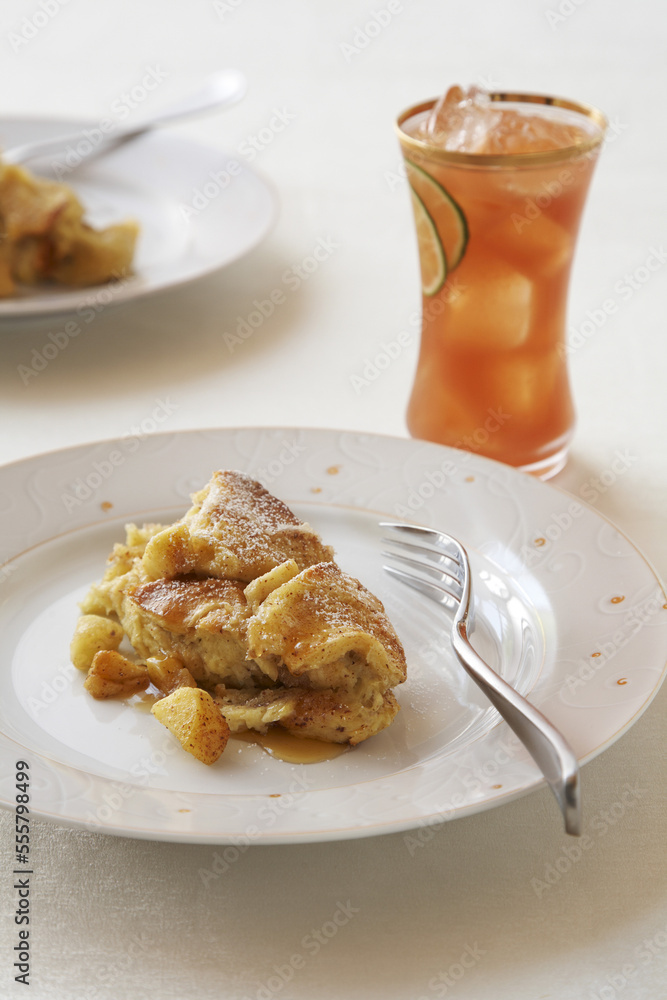 Apple bread pudding and maple syrup with glass of tropical fruit juice Apple bread pudding and maple syrup with glass of tropical fruit juice