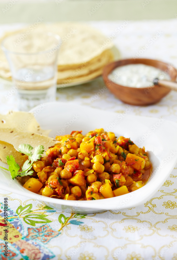 Bowl of chickpea curry with papadum and raita Bowl of chickpea curry with papadum and raita