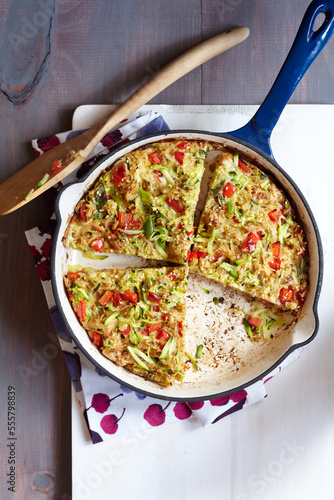 Sesame rice omelette with red peppers and green onions in an enamel skillet photo