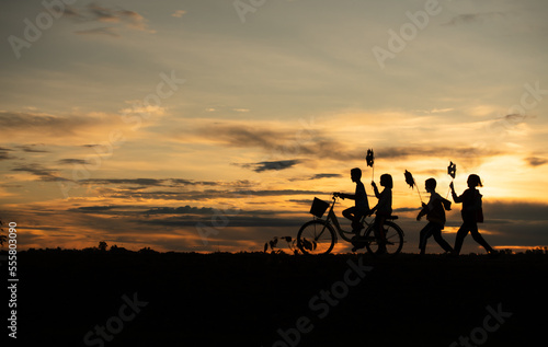 Children riding bicycles and running In the early light of the day as the sun shines