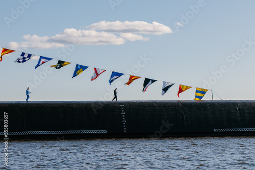 A view from a boat of a nuclear submarine with ballistic missiles in the waters of the Gulf of Finland, a sailor on deck, a submarine on the surface of the water.Russia, Kronstadt, 31.07.2021 photo