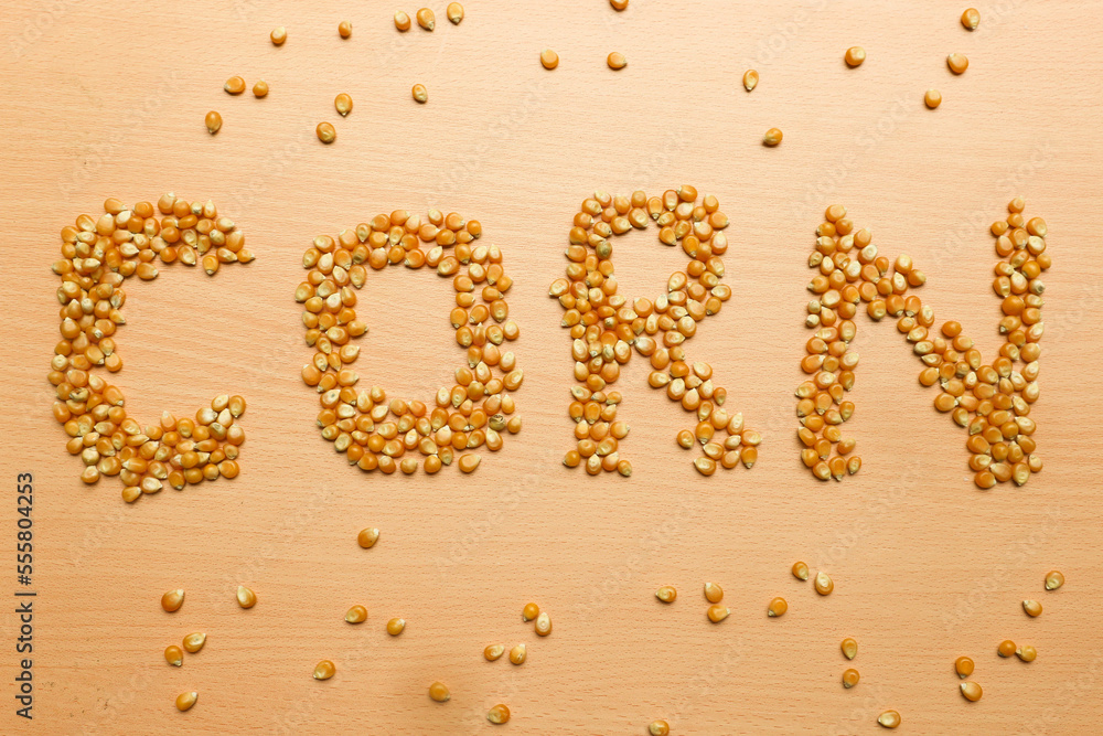 Pile of yellow corn seeds form the word 'CORN' on a brown wooden background, for popcorn. Pile of yellow corn seeds form the word 'CORN' on a brown wooden background, for popcorn.