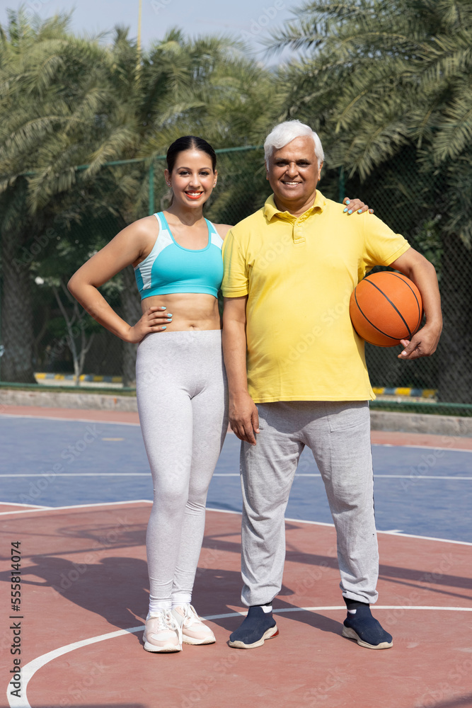 A happy father and teen daughter playing basketball outside at court. A happy father and teen daughter playing basketball outside at court.