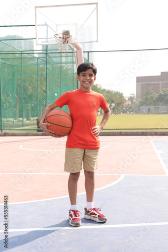 Canvas Print A portrait of a boy kid playing with a basketball in court.
