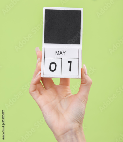 Block calendar with date may 01 in female hand on green background