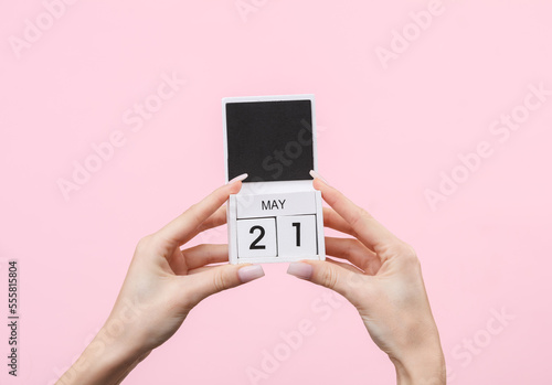 Block calendar with date may 21 in female hands on pink background