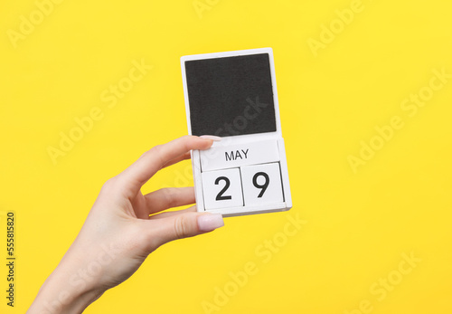 Block calendar with date may 29 in female hand on yellow background