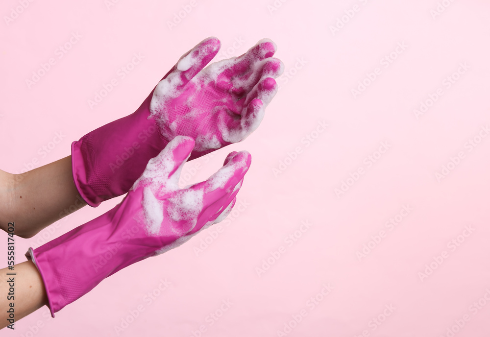 Hands in rubber gloves with foam on pink background. Copy space