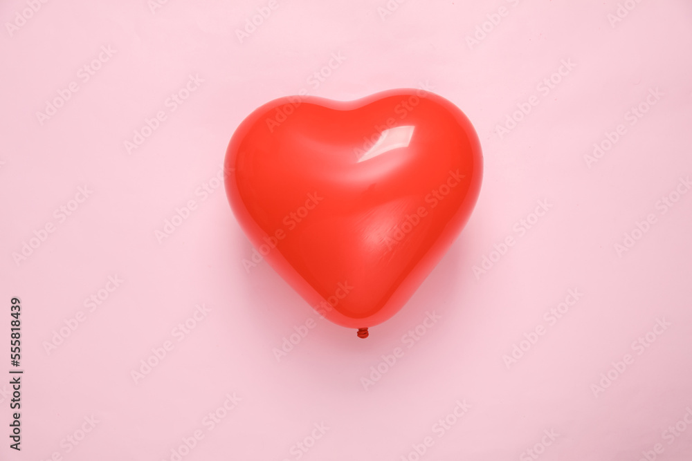 Red balloon in the shape of a heart on a pink background. Valentine's Day