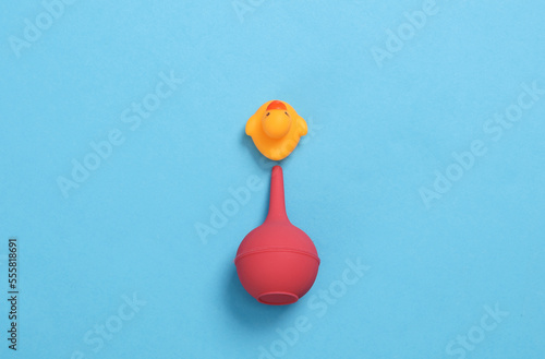 Enema with rubber duck on blue background. Creative layout