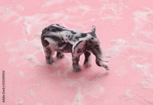 Toy elephant in foam on a pink background
