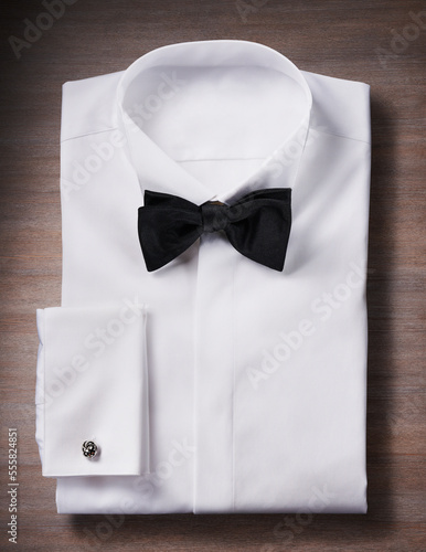 White, tuxedo shirt with a bow tie and cuff link, studio shot on wooden background photo