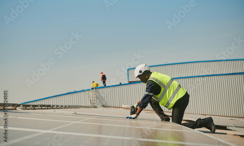 Engineer installing solar panels working on the roof.