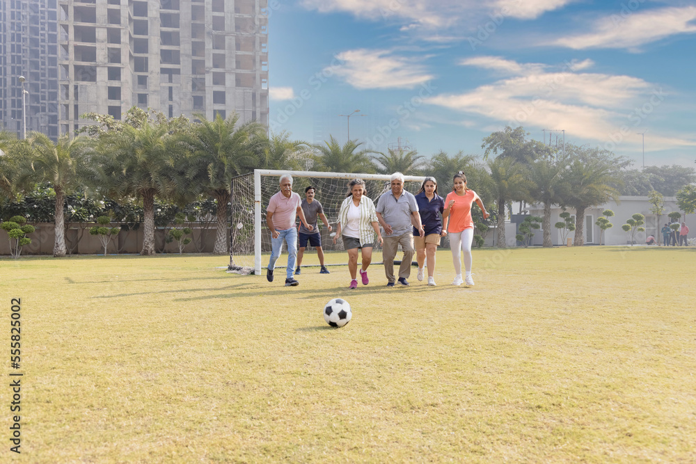 Happy multi generation family playing football together in the football ground. Happy multi generation family playing football together in the football ground.