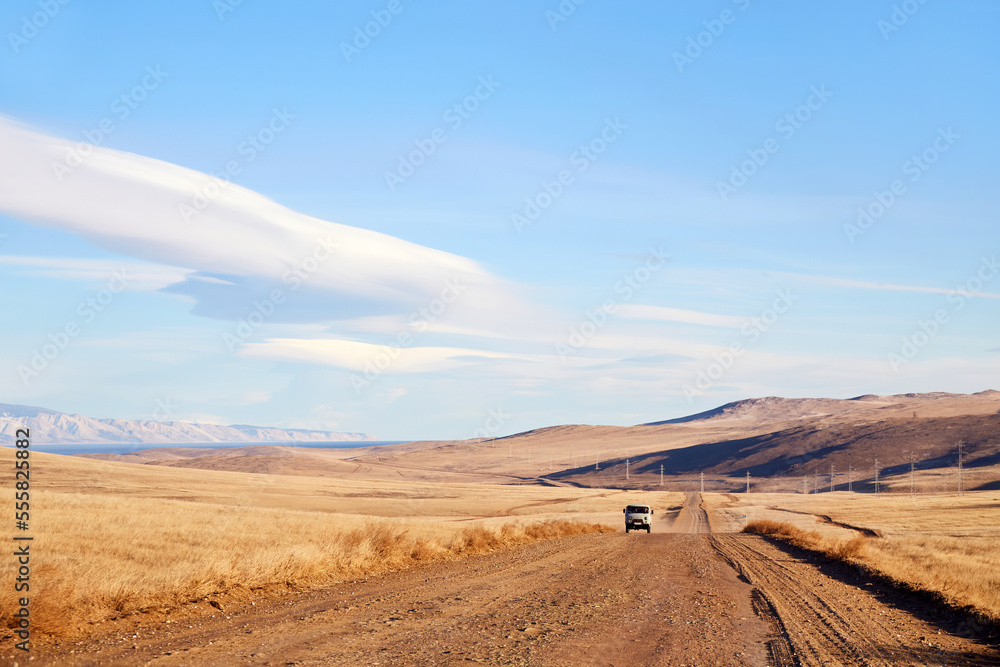 Landscape of Olkhon Island. A Russian SUV, a typical tourist bus called a Loaf, is driving along an empty road. A trip to Russia, to Lake Baikal.