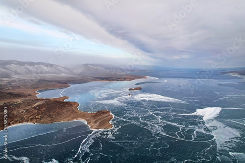 Frozen Lake Baikal in December from the air. Cloudy stormy sky  clear ice in the cracks. Winter landscape.