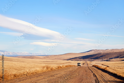 Landscape of Olkhon Island. A Russian SUV  a typical tourist bus called a Loaf  is driving along an empty road. A trip to Russia  to Lake Baikal.