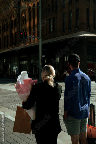 Couple Waiting at a Crosswalk with Flowers and Shopping Bags, Sydney Australia photo