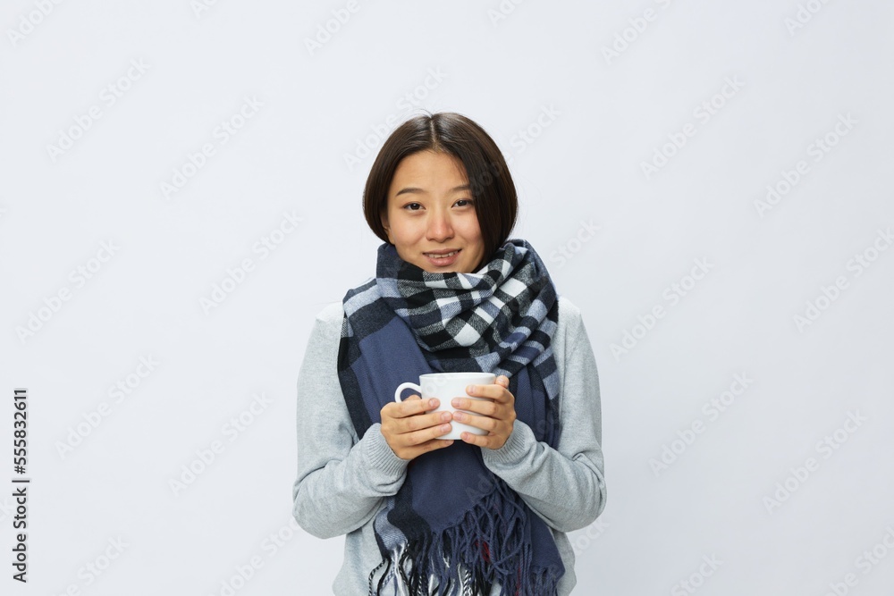 Asian woman cold flu holding a mug of tea smiling in plaid with fever sick of the virus on a white background Asian woman cold flu holding a mug of tea smiling in plaid with fever sick of the virus on a white background