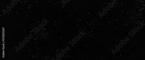 Flying dust particles on a black background, abstract real dust floating over black background for overlay, night sky graphic resources star on snow effect background 
