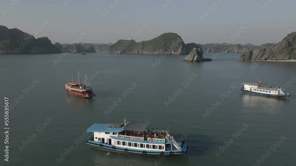 Tourists enjoy large tour boat cruises in Ha Long Bay Vietnam, aerial Tourists enjoy large tour boat cruises in Ha Long Bay Vietnam, aerial